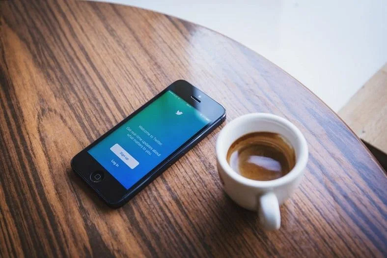 twitter statistic intro image with phone and coffee on table